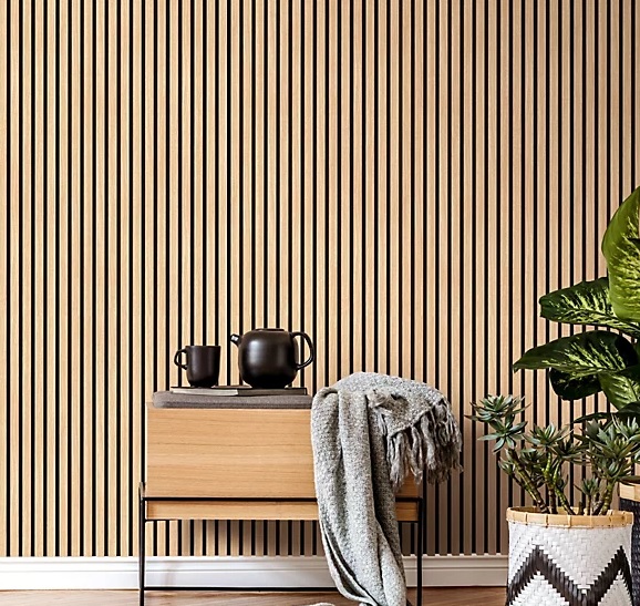 A professional joiner installs custom acoustic walnut wood slat paneling with integrated LED lighting and a video conferencing camera. The image shows precise joinery and acoustic felt backing.